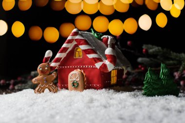 Siyah arka planda Noel süslemeleri olan Noel kurabiyesi evi. Geleneksel Noel pastası.