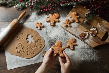 Karanlık arka planda Noel hediyesi zencefilli ekmek. Kadın elinde şekerli Noel kurabiyesi tutuyor. Üst görünüm