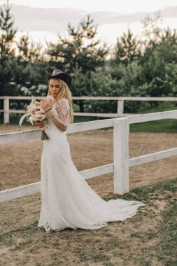 Beyaz gelinlik içinde bohem tarzında güzel bir gelinin portresi. Gün batımı.