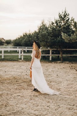 Beyaz gelinlik içinde bohem tarzında güzel bir gelinin portresi. Gün batımı.