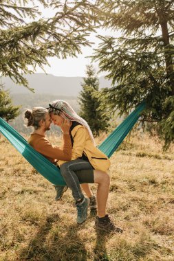 Parlak elbiseli güzel bir çift dağların arasında bir hamakta yatıyor. Gerçek duygular, aşk ve mutluluk..