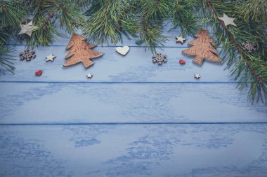 Noel veya Yeni Yıl arkaplanı: Çam dalları ve mavi tahtalarda biraz ahşap süslemeler.