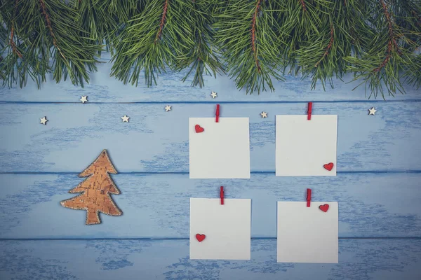 Christmas or New Year mock up: pine branches, white stickers with red clothespins and wooden Christmas tree on the blue boards.