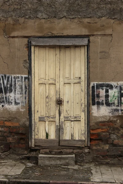 Verweerde geel deur in een muur — Stockfoto