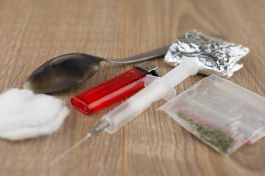 Kullanılan enjekte eden uyuşturucu kullanıcılarının işe alınması: şırınga, kararmış kaşık, pamuk ve bir çakmak folyo ve plastik pakette paketlenmiş bir ilacın yanında, kısa odaklı