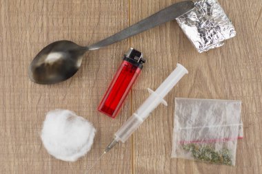 Kullanılan enjekte eden uyuşturucu kullanıcılarının alımı: şırınga, kaşık, pamuk ve alüminyum folyoya sarılı bir uyuşturucunun yanında uzanan çakmak ve plastik bir torba