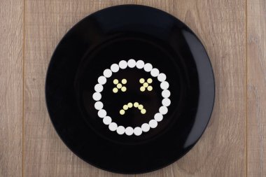 tedavi kimyasalları: hoşnutsuzluğu ifade eden bir gülümseme beyaz tabletleri siyah bir tabakta yeniden odaklamaktan oluşur