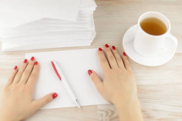 neat office work: office worker prepared a workspace handy: Envelopes, pen and tea placed to continue active work