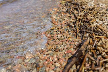 the shore line: Brightly colored rocks washed by waves freshwater lakes with crystal clear water, natural waste made by the water on the shore