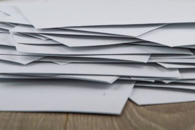 straining at work: a Huge disorderly pile of empty envelopes with working mail on the accountant's Desk, side view