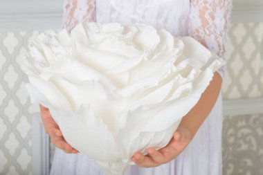 Gelin dantelli elbisesinin ellerinde büyük ipek bir çiçek