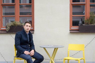 Adam kafenin yakınındaki bir masada oturuyor, masada aletler yatıyor.