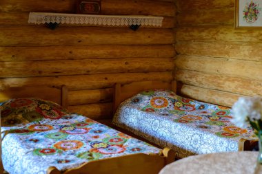 İki yataklı, masalı ve raflı ahşap bir kır evinde bir oda.