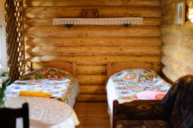 İki yataklı, masalı ve raflı ahşap bir kır evinde bir oda.