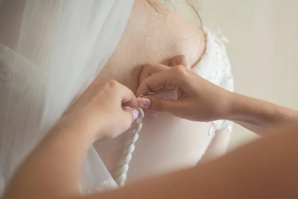 bridesmaid button up buttons on the back of the white bridal wedding dress with a veil