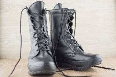 Rus askeri botlarını çimdiklemek için blok sistemi. Ahşap zeminde aşınma ve toz izleri olan bir çift ayakkabı.