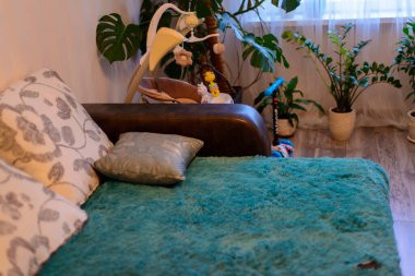 Odanın köşesinde kanepe, çocuk oyuncakları ve yeşil bitkiler var.