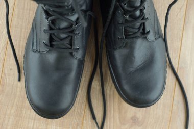 Ahşap zeminde aşınma ve toz izleri olan bir çift Rus askeri botu.