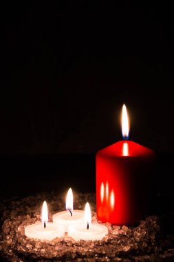 Banyo ve aromaterapi için hazırlıklar: Dört dekoratif mum aromatik deniz tuzunda dikey ve koyu lavanta kokulu duruyor.