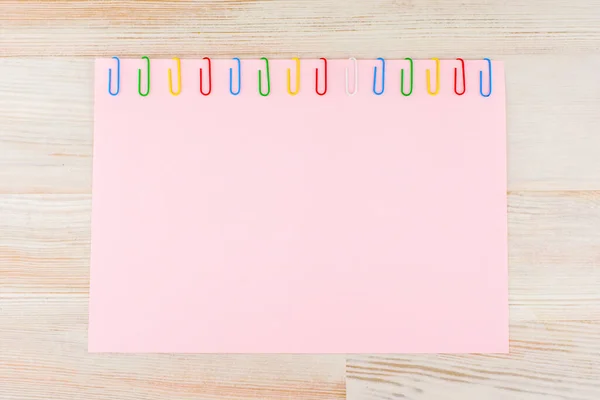 Лист Розовой Бумаги Закрепленный Разноцветными Скрепками Светящемся Столе Горизонтальном Повороте — стоковое фото