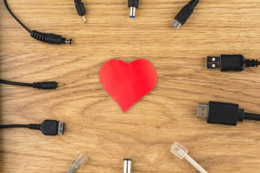 Aşk bağları için beklemek: kırmızı kalp ve ona bağlanamayan bir sürü farklı buji ve şarj aleti, perspektif olarak