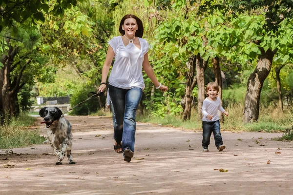 Jovem mãe com criança e cachorro desfrutando de seu tempo na natureza , — Fotografia de Stock