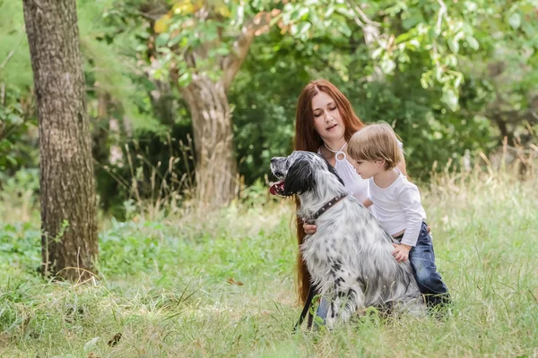 Jovem mãe com criança e cachorro desfrutando de seu tempo na natureza , — Fotografia de Stock