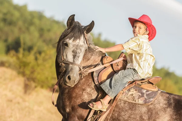 Ritratto all'aperto di un giovane ragazzo felice che cavalca un cavallo in fattoria, rura — Foto Stock