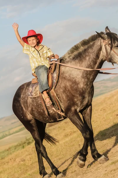 Utomhus porträtt av ung glad pojke som rider en häst på gården, rura — Stockfoto