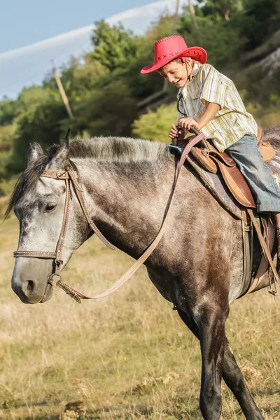 Utomhus porträtt av ung glad pojke som rider en häst på gården, rura — Stockfoto