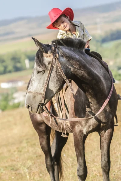 Utomhus porträtt av ung glad pojke som rider en häst på gården, rura — Stockfoto