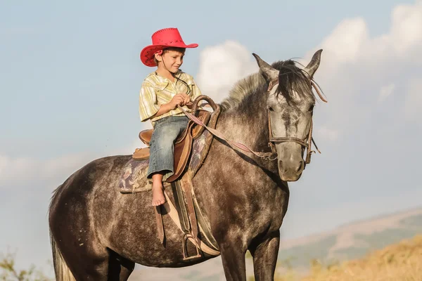 Außenporträt eines glücklichen Jungen auf einem Pferd auf einem Bauernhof, rura — Stockfoto