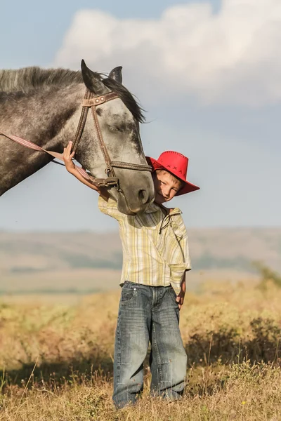 Außenporträt eines glücklichen Jungen auf einem Pferd auf einem Bauernhof, rura — Stockfoto