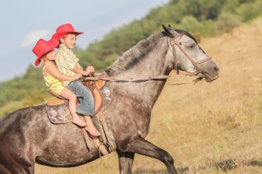 iki genç mutlu çocuklar bir çiftlikte, açık portre üzerinde binicilik