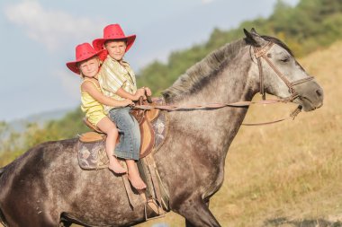 iki genç mutlu çocuklar bir çiftlikte, açık portre üzerinde binicilik