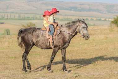 iki genç mutlu çocuklar bir çiftlikte, açık portre üzerinde binicilik