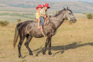 iki genç mutlu çocuklar bir çiftlikte, açık portre üzerinde binicilik
