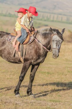 iki genç mutlu çocuklar bir çiftlikte, açık portre üzerinde binicilik