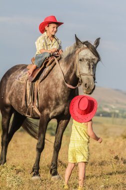 iki genç mutlu çocuklar bir çiftlikte, açık portre üzerinde binicilik