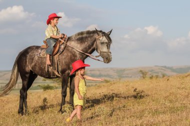 iki genç mutlu çocuklar bir çiftlikte, açık portre üzerinde binicilik