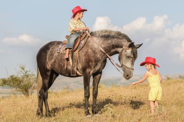 iki genç mutlu çocuklar bir çiftlikte, açık portre üzerinde binicilik