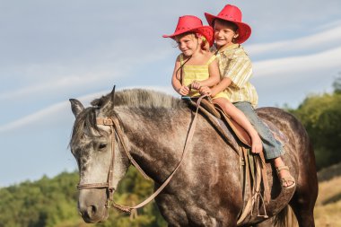 iki genç mutlu çocuklar bir çiftlikte, açık portre üzerinde binicilik