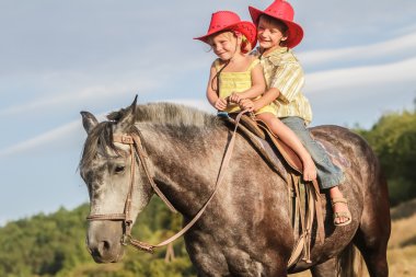 iki genç mutlu çocuklar bir çiftlikte, açık portre üzerinde binicilik