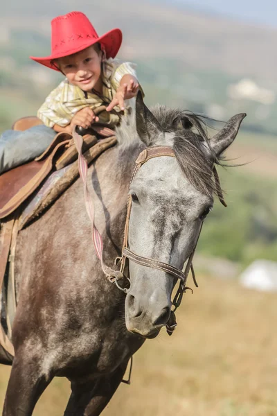 Utomhus porträtt av ung glad pojke som rider en häst på gården, rura — Stockfoto