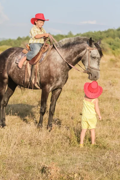 Two young happy kids riding a horse on farm, outdoor portrait on — Stock Photo, Image