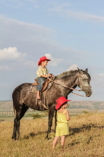 Dwóch młodych szczęśliwy kids na koniu na farmie, odkryty portret na — Zdjęcie stockowe