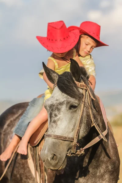 Two young happy kids riding a horse on farm, outdoor portrait on — Stock Photo, Image