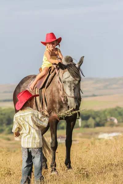 Two young happy kids riding a horse on farm, outdoor portrait on — Stock Photo, Image