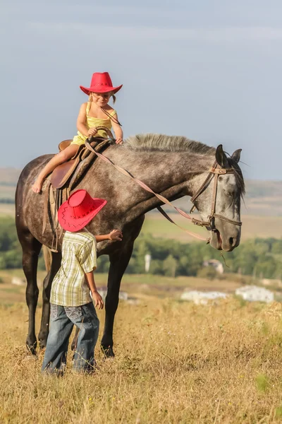 Twee jonge gelukkige jonge geitjes het berijden van een paard op de boerderij, outdoor portret op — Stockfoto