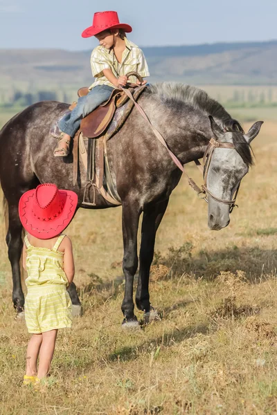 Two young happy kids riding a horse on farm, outdoor portrait on — Stock Photo, Image